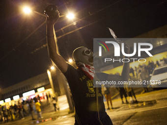 A protestor standing in the middle of W. Florissant Ave. in Ferguson Mo. already with a gas mask on, holds a 