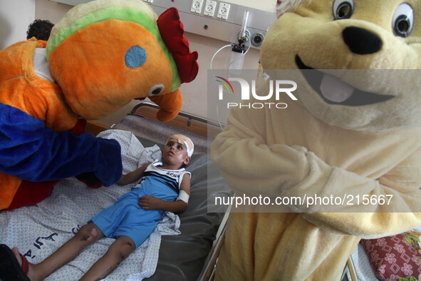 A Palestinian boy, whom medics said was wounded by Israeli shelling, is visited by members of a local aid society wearing costumes at a hosp...