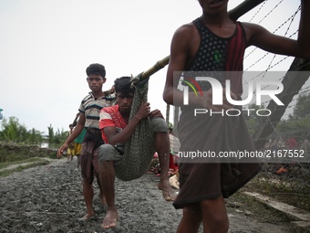 Rohinga people carry a man in a sack and walk through the border net to cross at Mongdaw, Myanmar. September 6, 2017  Rohingya are a Muslim...