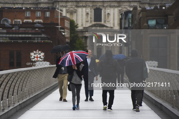 People are seen walking on Millennium Bridge holding umbrellas, due to the heavy rain, London on September 8, 2017.  