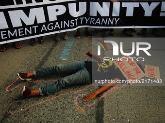A protester lies down on the road as a mock victim of extrajudicial killings during a rally against extrajudicial killings allegedly done by...