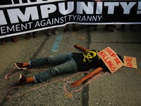 A protester lies down on the road as a mock victim of extrajudicial killings during a rally against extrajudicial killings allegedly done by...