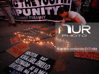 A protester lights candles around a mock crime scene during a rally against extrajudicial killings allegedly done by government forces and v...