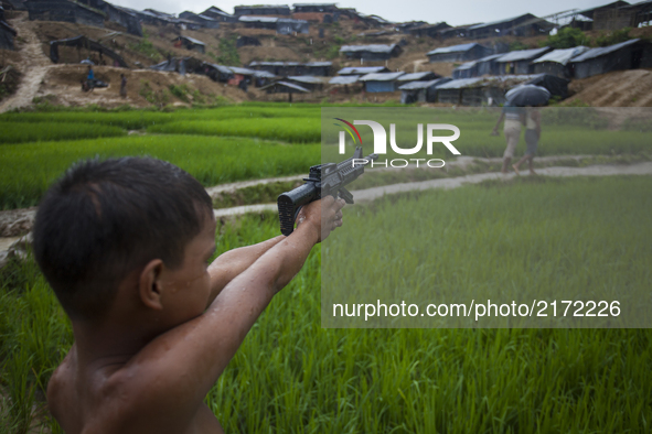 Rohingya ethnic minority boy playing with a gun with other boys at a temporary makeshift camp after crossing over from Myanmar into the Bang...
