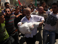 Palestinian mourners carry The body  child Ali Mohammed Deif ,, whose wife and child were killed in an air strike in Gaza late on August 19,...