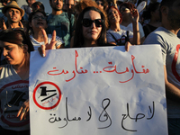 A female protester makes a victory sign as she holds a placard that reads in Arabic 