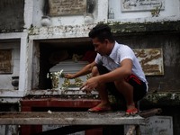 A cemetery caretaker places flowers offered by a mourner to the tomb of slain teenager Reynaldo De Guzman during funeral rites in suburban P...