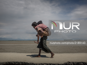 A Rohingya refugee is carrying his mother on his back at Shahpirer Dip, Teknaf, Bangladesh; September 14, 2017. Bangladesh will use troops t...