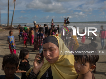 A Rohingya woman talks with her relatives on a mobile phone after crossing the Naf river by boat. Shahpirer Dip, Teknaf, Bangladesh; Septemb...
