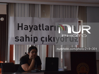 A woman sits in front of a banner reading 'We protect our lives' prior to women's meeting against violence and abuse in Ankara, Turkey on Se...