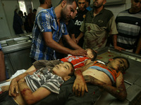The bodies of three children from the al-Rifi family killed in an Israeli air strike lay on a gurney in front of a covered corpse of an unid...