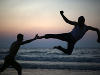 Palestinian youths jumps on the beach as the sun sets over Gaza City on 18 September 2017.
 (