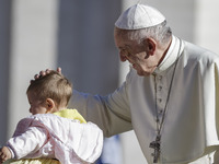 Pope Francis caresses a baby as he arrives to celebrate his Weekly General Audience in St. Peter's Square in Vatican City, Vatican on Septem...