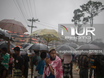 Rohingya refugees wait for relief under umbrella during rainfall at Balukhali Refugee Camp, Cox’s Bazar, Chittagong, Bangladesh. September 1...