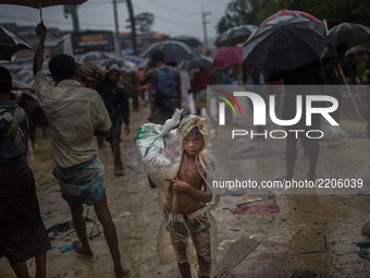 A kid carries relief and walks covered by plastic as there is heavy rainfall at Balukhali Refugee Camp, Cox’s Bazar, Chittagong, Bangladesh....