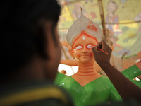 A 26yrs old Nepalese artist, ARUN PANDIT paints on clay idol of the Hindu Goddess Durga, which is being transported to worship in different...