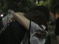 Trenton Meyer hugs his sister, Melanie Meyer as rain falls outside during Monday night's protest. Meyer said she hadn't seen her brother in...