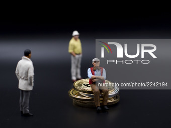 Miniature figures near Bitcoin physical token. (