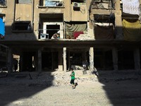 A child walks beside destruction rubble of a building in the rebel. held town of Douma, on the eastern outskirts of Damascus, on October 7....