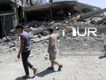 Palestinians walk next to the rubble of house destroyed after Israeli air strikes, in beit lahya in the northern Gaza Strip, on 25 August 20...