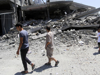 Palestinians walk next to the rubble of house destroyed after Israeli air strikes, in beit lahya in the northern Gaza Strip, on 25 August 20...