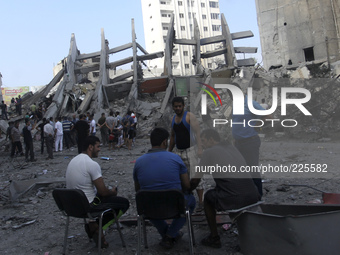 Palestinian men sit infront of the rubble of the destroyed 15-storey Basha Tower after an Israeli airstrikes in Gaza City, on 26 August 2014...