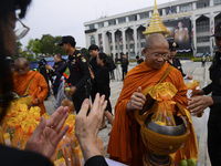 Thai Buddhist devotees give alms to a Buddhist monk in front of Bangkok's City Hall on October 13, 2017. King Bhumibol Adulyadej passed away...