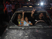 Palestinians ride in a damaged car as they celebrate with others what they said was a victory over Israel, following a ceasefire in Gaza Cit...