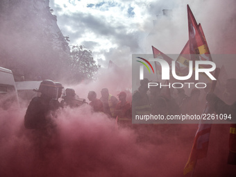 Metalworkers and police officers are surrounded by smoke as they march with banners and flags in the streets of Paris on October 13, 2017. S...