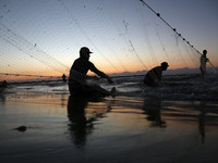 Palestinian fishermen pull in their net along the shore of the Mediterranean Sea, as dusk approaches in Gaza City,on October 15, 2017. (