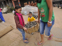 Kids helping his sister to carrying clay pot lamps, being sun dried for upcoming Tihar or Deepawali Festival on his workshop at Pottery Squa...