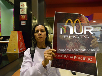 Protesters wave placards and leaflets during an animal rights march outsideand inside McDonald's restaurant on São Paulo on October 17, 2017...