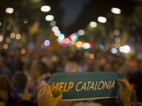 A protester holds a placard reading 'Help Catalonia' during candle-lit demonstration in Barcelona against the arrest of two Catalan separati...
