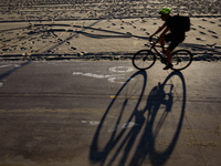 A man rides a bike along the promenade in the Venice Beach area of Los Angeles, California on October 17, 2017. Venice Beach is the 2nd-larg...