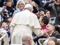 Pope Francis caresses a child as he arrives in St. Peter's Square at the Vatican, for his weekly general audienc,e Wednesday,  (
