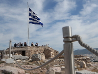 A Greek flag waves as tourists enjoy the view atop of the ancient Acropolis hill in Athens. Greece, Wednesday, October 18, 2017 (