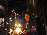 A girl smiles as holding beautiful sparklers (fire crackers) in hands during Laxmi Puja as the procession of Tihar or Deepawali and Diwali c...