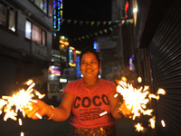 A woman smiles as holding beautiful sparklers (fire crackers) in hands during Laxmi Puja as the procession of Tihar or Deepawali and Diwali...
