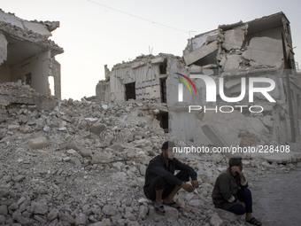 Two men sitting on the ruins of a building because of regime forces shelling on Aleppo city, on August 28, 2014. (Photo by Karam Almasri/Nur...