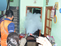 A state government health official fumigates an area to kill mosquitoes with a portable smoke fogger in order to combat Dengue, in Kolkata,...