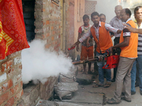 A state government health official fumigates an area to kill mosquitoes with a portable smoke fogger in order to combat Dengue, in Kolkata,...