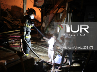 A firefighter uses a flashlight to illuminate the way as residents pass after a major fire hit a slum located in the Campo Belo neighborhood...