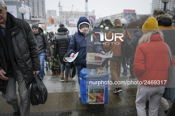 A woman is seen handing out free newspapers in central Warsaw on February 8, 2018. 