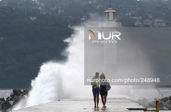 People enjoy the strong wind ang hight sea waves at the Black sea port of Varna east of the Bulgarian capital Sofia, Tuesday, Sep. 16, 2014....