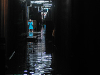 A child submerged in flood water caused by Tropical Storm Fung-Wong, takes photos as he stands beside their stall inside a wet and dry marke...