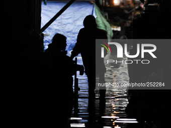 A silhouette image of men wading in flood water caused by tropical storm Fung Wong inside a wet and dry market in Manila, Philippines on 19...