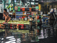A vendor sits by her stall submerged in flood water caused by tropical storm Fung Wong inside a wet and dry market in Manila, Philippines on...