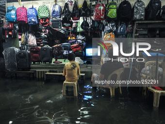 Vendors watch television as they sit by their stall submerged in flood water caused by tropical storm Fung Wong inside a wet and dry market...