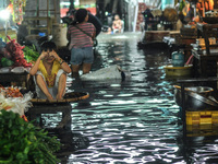 A child is seen sitting beside a vegetable stall submerged in flood water caused by tropical storm Fung Wong inside a wet and dry market in...