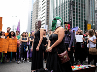 Women with masks stand around a coffin symbolizing women who die from abortions that are conducted clandestinely and unsafety during a demon...